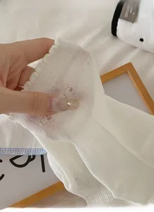 Close-up of white breathable socks with high elastic ribbing and wavy ruffled edges