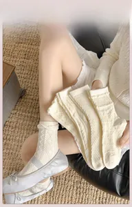 Detail von cremeweißen JK-Socken mit Rauten- und Zopfstrickmuster aus weicher Baumwolle
