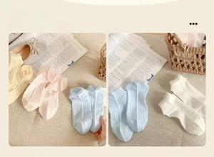 Détail de la bordure en dentelle et texture coton de chaussettes pastel en quatre tons