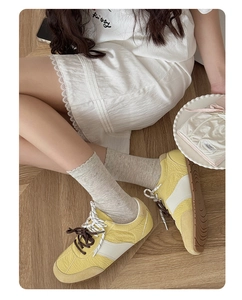Detail of yellow patchwork sneakers with textured fabric and dual-tone patterned laces