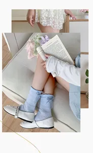 Close-up of light blue mesh crew socks with lace trim and bow detail in Mary Janes