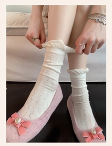 Close-up of white lace ruffle socks with hollow knit pattern and pink ballet flats