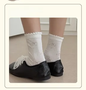 Detail of white crew socks with dark bow patterns and elegant wavy ruffle cuffs on the feet