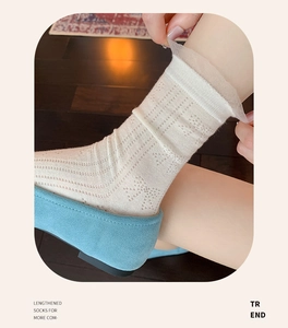 Detailed view of white cotton mid-calf socks with lace trim and hollow jacquard pattern