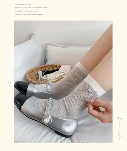 Close-up of silver Mary Jane shoes with pearl chains and knit socks with silver bows
