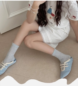 Detail of light gray ribbed knit socks with wavy lace cuffs paired with blue flat shoes