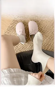 Nahaufnahme cremeweißer Wadenstrümpfe mit Rautenstrickmuster und elastischen Bündchen