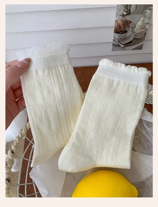 Detail of white cotton crew socks with heart jacquard patterns and delicate lace ruffles