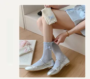 Close-up of thin knit socks with ruffle trim and plaid bow detail in light blue color