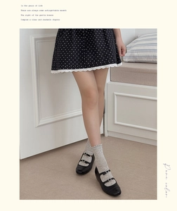 Detail of grey ruffled socks with black Mary Jane shoes and polka dot skirt