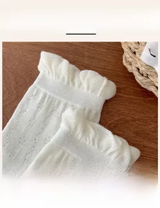 Detailed close-up of white mesh socks with elegant lace trim and ruffle cuffs