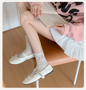 Detail of white striped crew socks with pink bows and Mary Jane shoes on a model