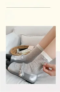 Detail of grey mesh socks featuring silver cord bows and contrast Mary Jane shoes