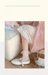 Nahaufnahme weißer Spitzen-Socken mit rosa Schleifen und Rüschen aus Organza-Stoff