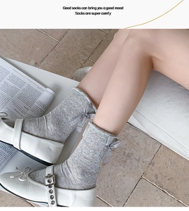 Detail of grey hollow mesh socks with lace trim and black and white striped bow