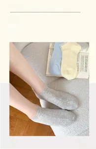Détail de chaussettes en dentelle ajourée grises, bleues et jaunes sur tapis doux