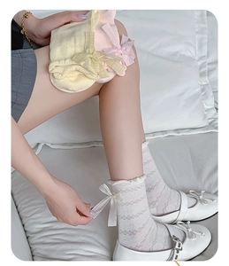 Detail of hollow mesh knit socks featuring ruffled cuffs and satin ribbon bows