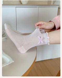 Detail showing elastic lettuce edge cuff and pink plaid bow on light knit socks