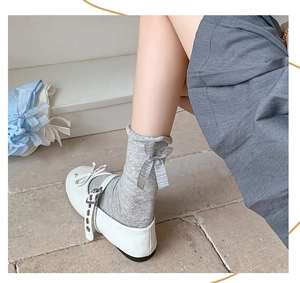 Detail of grey hollow knit socks featuring a silver-grey ribbon bow and Mary Jane shoes