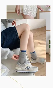 Close-up of grey ribbed cotton socks with blue stripe and beige retro sneakers