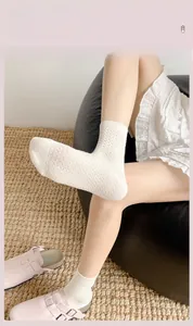 Detail von cremeweißen Socken mit hohlem Rautenmuster und gerippten Bündchen am Bein