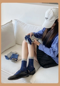 Détail du tricot des chaussettes mi-mollet bleu marine et gris avec bords côtes et fleurs
