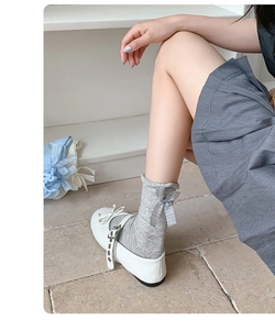 Detail of grey hollow mesh mid-calf socks featuring a delicate bow and Mary Jane shoes
