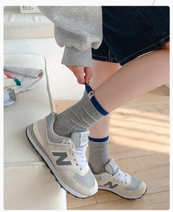 Close-up of gray striped crew socks with blue trim and retro sneakers in a lifestyle setting
