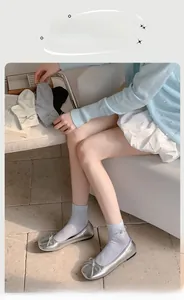 Dettaglio di calze in cotone stile balletto con fiocco e ciondolo a cuore argento