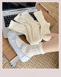 Detail von cremefarbenen Zopfstricksocken mit Rautenmuster und elastischen Rippbündchen