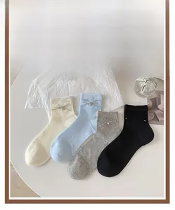 Dettaglio calzini a coste in cotone con fiocco e ciondolo a cuore in vari colori pastello