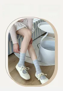 Detail of light blue striped mesh socks with delicate lace trim and white Mary Jane shoes