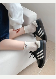 Detail von cremefarbenen Polka-Dot-Socken mit Snoopy-Stickerei und schwarzen Sneakern