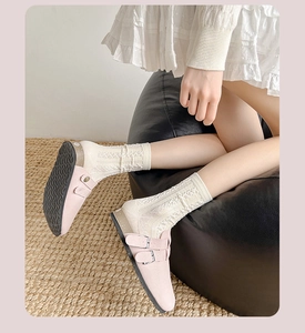 Details von rosa Wildleder-Clogs mit zwei Schnallen und weißen Zopfstricksocken