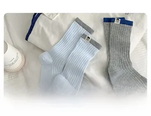 Close-up of ribbed cotton socks with character patches, blue and grey college style colors