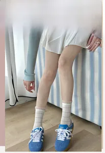 Detail of white checkered crew socks paired with blue suede sneakers in a casual style