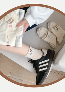 Detail von cremeweißen Socken mit süßer Tierstickerei und bunten Farbtupfern für Damen