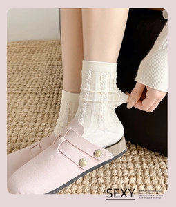 Detailaufnahme cremeweißer Socken mit Zopfmuster und elastischem Strickbündchen