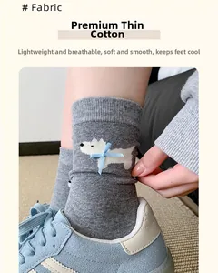Detail of gray cotton socks featuring white puppy patterns and light blue ribbon bows