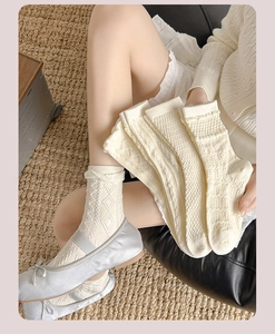 Detail von cremeweißen Socken mit Retro-Rauten-Hohlmuster und weicher Strickstruktur
