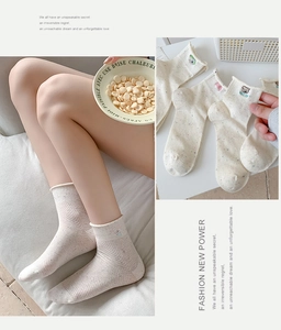 Detail von cremefarbenen Baumwollsocken mit bunten Punkten und Bärenbestickung