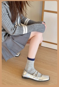 Détail de chaussettes grises de style preppy avec bord bleu marine et Mary Janes argentées