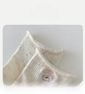Details von Socken aus weißem Noppengarn mit Tierstickerei und elastischem Rollrand