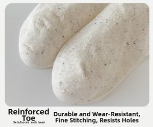 Nahaufnahme der verstärkten Zehennaht und buntem Noppengarn auf cremefarbenen Socken