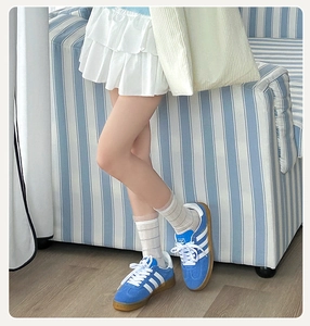 Detail of blue suede retro sneakers with white stripes and gum rubber outsole