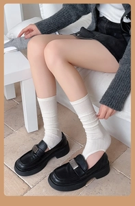 Gros plan de mocassins en cuir noir à plateforme avec boucles et chaussettes blanches