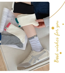 Close-up of ribbed cotton crew socks with cloth tags worn with stylish sneakers