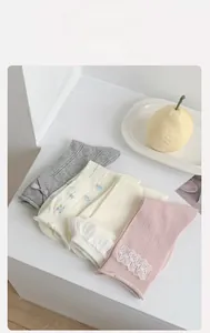 Dettaglio di quattro calze in pizzo floreale con fiocchi in grigio, crema e rosa