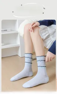 Detail of light blue lace trim socks with triple layered dark grey ruffles and rib knit