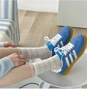 Detail view of Gazelle blue suede sneakers paired with thin plaid mesh crew socks